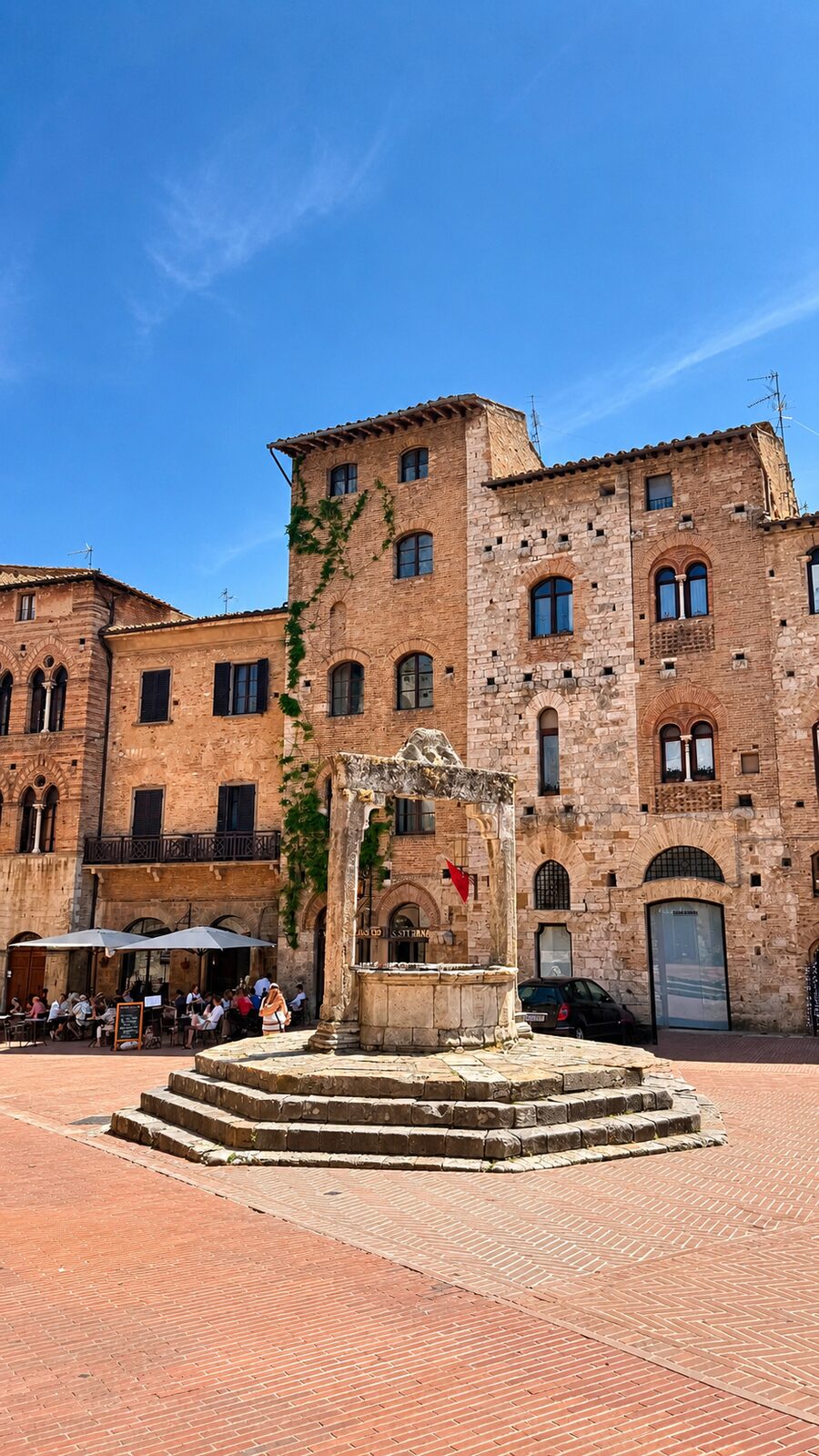 Studnia na placu w San Gimignano otoczona średniowiecznymi kamienicami