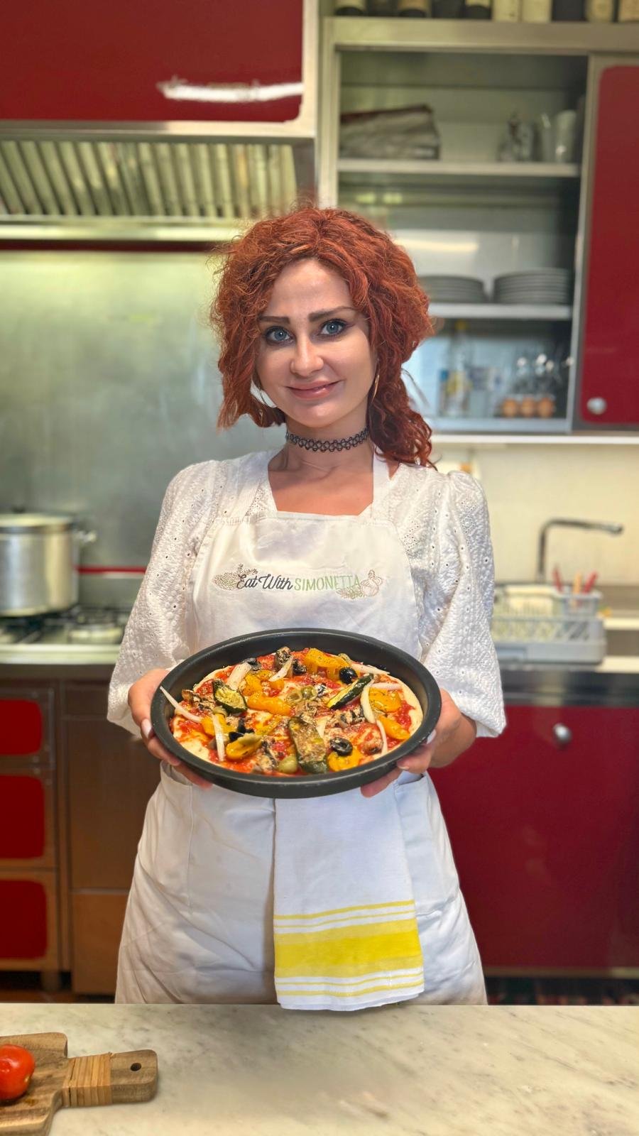 Kobieta prezentująca domową pizzę w kuchni