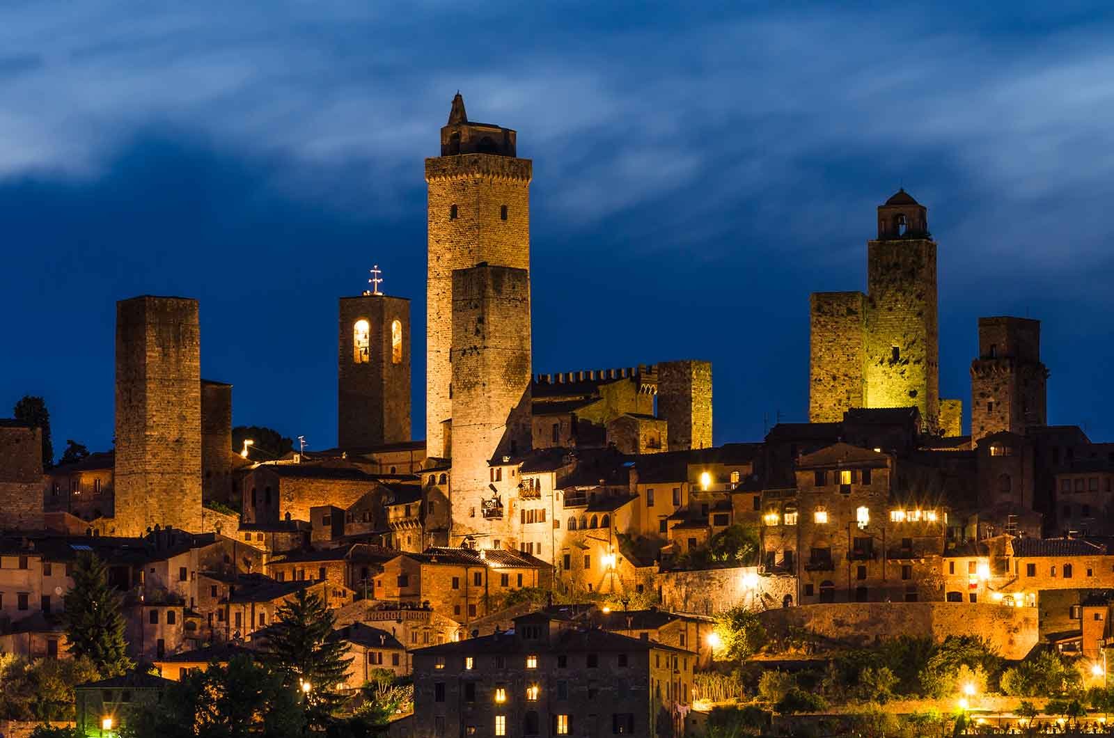 Nocna panorama średniowiecznych wież San Gimignano oświetlonych ciepłym światłem